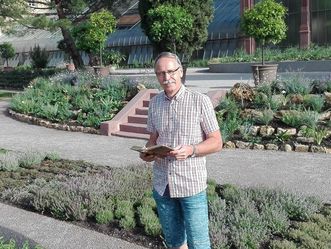 Botanischer Garten Karlsruhe, Der Gartenleiter Thomas Huber mit dem Gartenführer vor den Schaugewächshäusern.